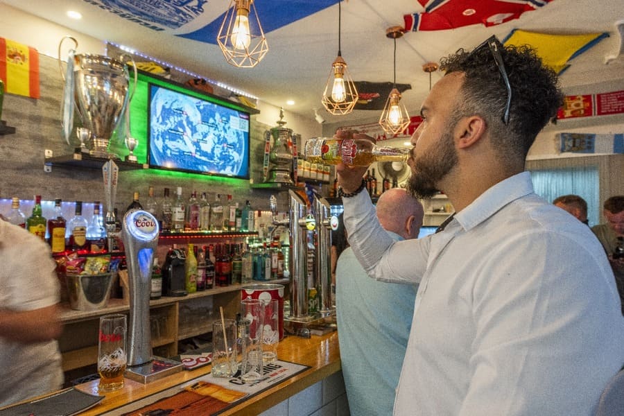 Alley Cats personas en bar observando televisor